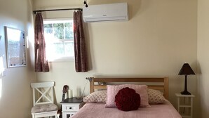 A bedroom with a bed, a chair, a guitar, a lamp, and an air conditioner. - Cozy 1-bedroom studio barn cottage in tranquil Winters (Winters)
