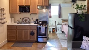 A compact kitchen with wooden cabinets, a microwave, stove, and a refrigerator. - Cozy 1-bedroom studio barn cottage in tranquil Winters (Winters)