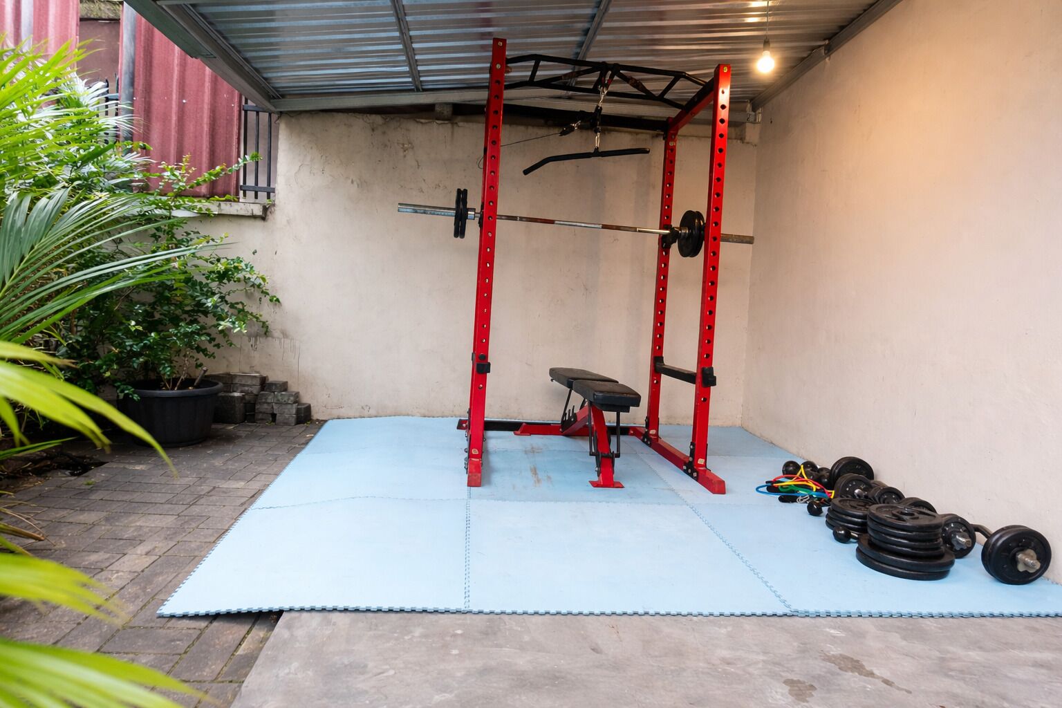 A home gym with a squat rack, bench, and various weights.