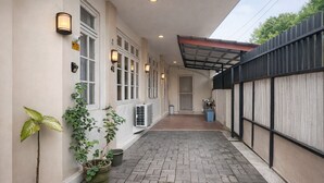 A narrow corridor with a tiled floor, potted plants, and a covered area with a metal roof. - Homestay Area Malioboro ABC Homestay (yogyakarta)