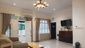 A spacious living room with a sofa, a wooden coffee table, a piano, and a television. - Homestay Area Malioboro ABC Homestay (yogyakarta)