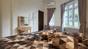 A hotel room with a bed, a vanity with a mirror, a wardrobe, and a window with curtains. - Homestay Area Malioboro ABC Homestay (yogyakarta)