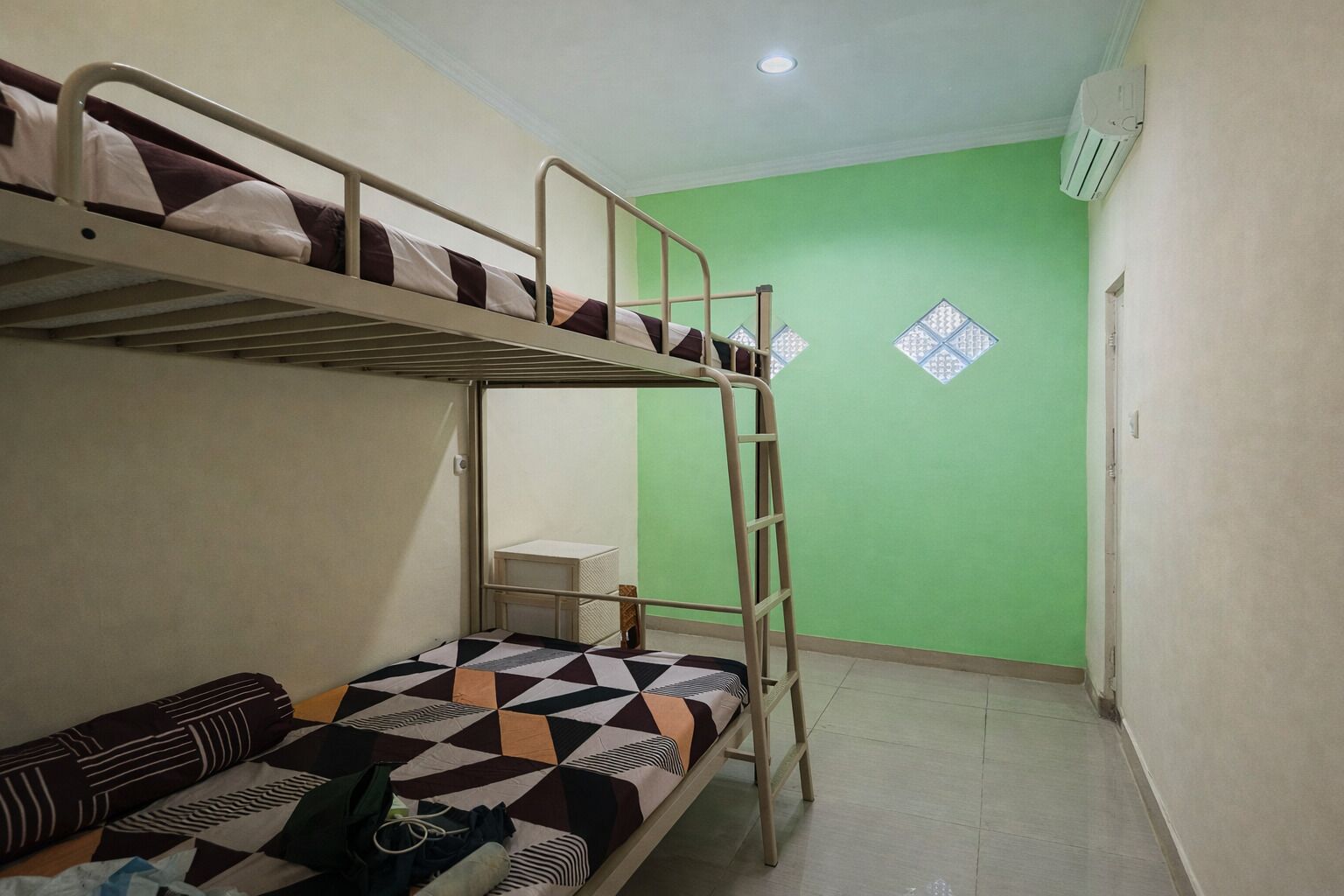Habitación con literas, una mesita pequeña y una colcha estampada.