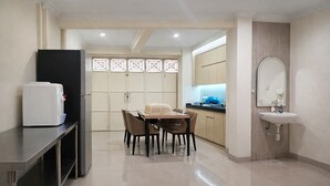 A modern kitchen with a dining table, chairs, a refrigerator, and a sink. - Homestay Area Malioboro ABC Homestay (yogyakarta)
