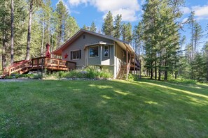 Eine Hütte mit einer Terrasse, Treppe und einem umliegenden Wald.
