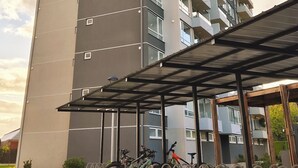 A tall residential building with multiple balconies and a covered bike parking area. - Moderno impecable Cercano a terminales (Temuco)