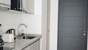 A modern kitchen with a built-in oven, a sink, and a microwave. - Moderno impecable Cercano a terminales (Temuco)