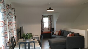 A modern living room with a dining area, grey sofa, and patterned curtains. - Binnian View Apartment - Sleeps 4 (Newry)