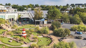 Un parcours de minigolf avec un phare, entouré de verdure et doté d’un espace de stationnement.