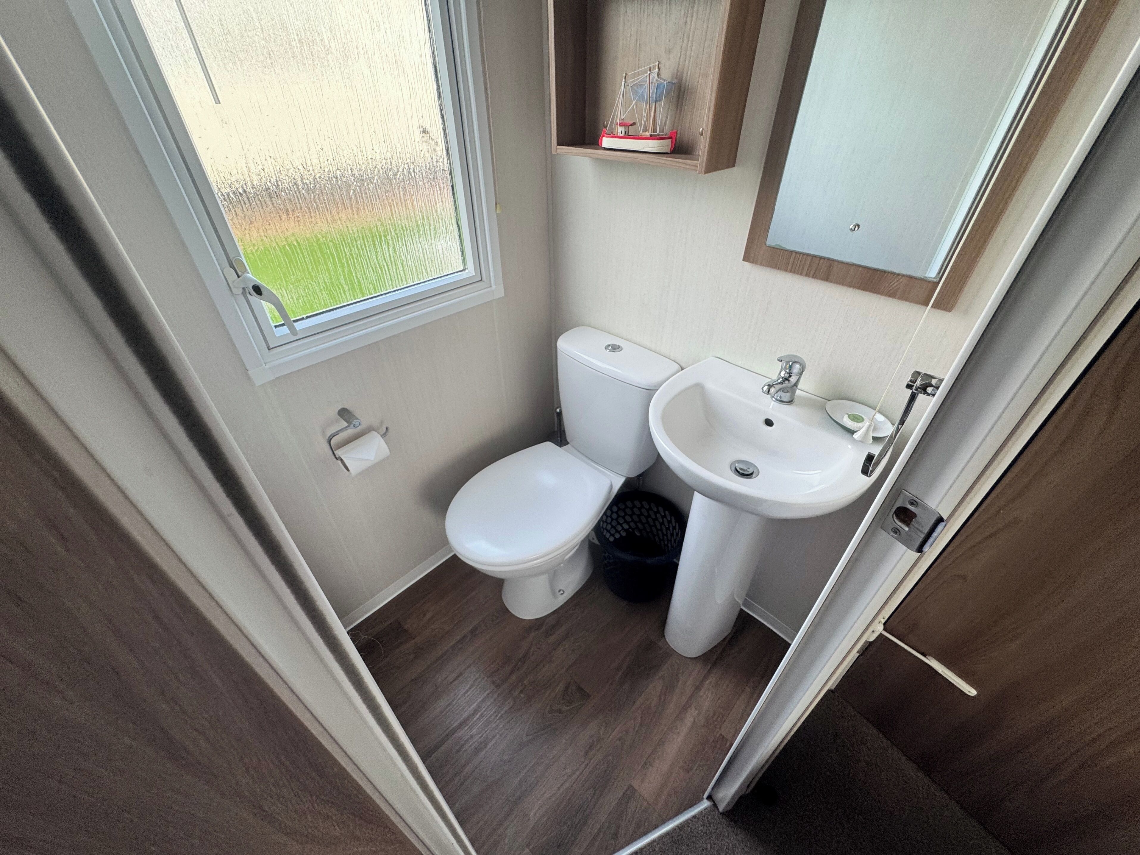 A compact bathroom with a toilet, sink, and window.