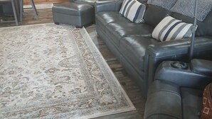 A modern living room with a leather sofa, a patterned rug, and wooden flooring. - Beautiful Cabin Perfect For Your Family Gathering in the North GA Mountains (Mineral Bluff)
