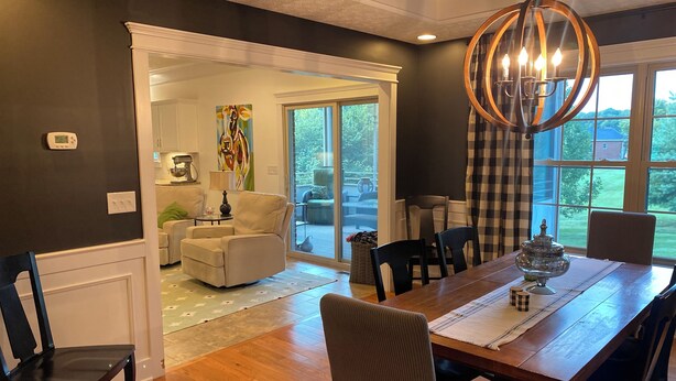 A dining area with a wooden table and chairs, a chandelier, and a view of the outdoors through large windows. - Large Home with Entertainment Options Galore (Elizabethtown)