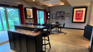 A modern kitchen with a central island, dining area with chairs, and a large window with curtains. - Large Home with Entertainment Options Galore (Elizabethtown)