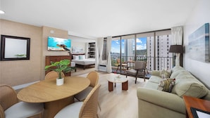 Ein modernes Wohnzimmer mit Essbereich, einer Couch, einem Fernseher und einem Balkon mit Stadtblick.