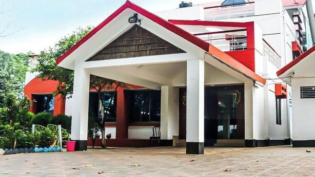 A building with a red and white facade, a covered entrance, and a tiled ground. - Almas Hotel Sylhet  (Sylhet)