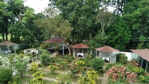 A garden with various plants and flowers, a gazebo, and a small building with a red roof. - Almas Hotel Sylhet  (Sylhet)