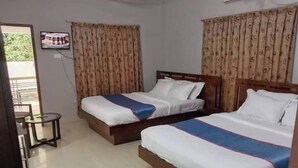 A hotel room with two beds, a small table, and a television on the wall. - Almas Hotel Sylhet  (Sylhet)