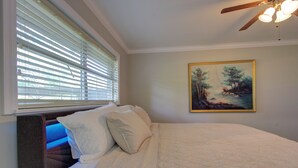 Una camera da letto con un letto, una ventola a soffitto e un quadro appeso al muro.