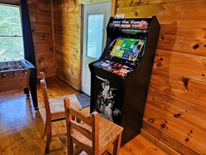 A wooden room with a foosball table, a chair, and a Capcom arcade game. - Family Fun Cabin w/ Views - Hot Tub, Sauna, Arcade, Pool Table, EV (Pigeon Forge)