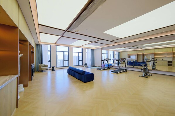 A spacious room with large windows, a blue sofa, and exercise equipment.