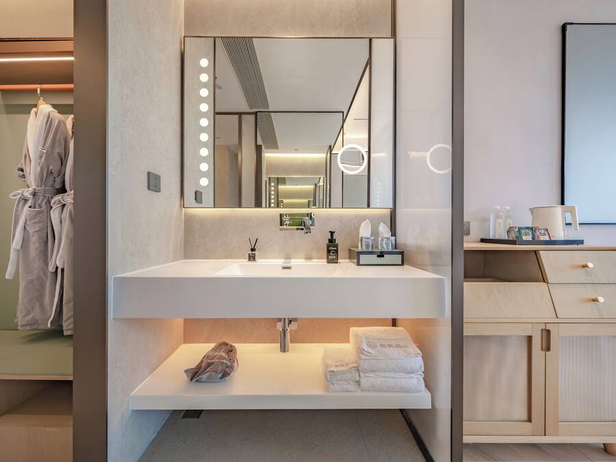 A modern bathroom with a large mirror, vanity, and a wooden cabinet.