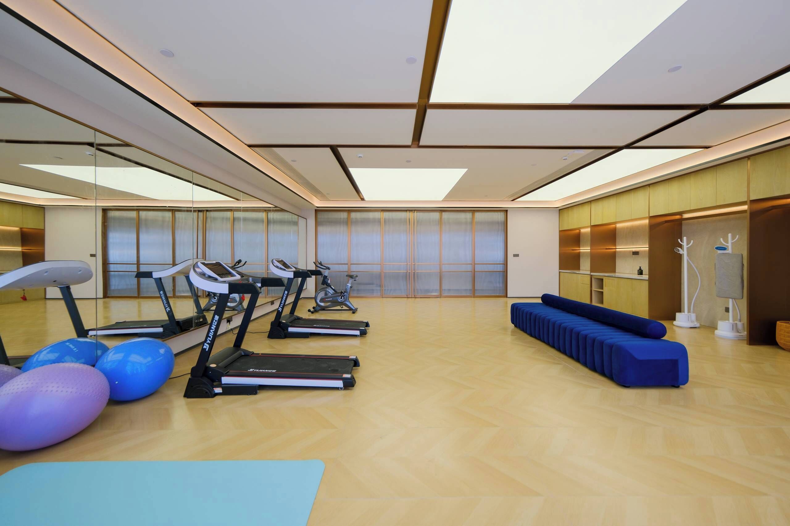 A spacious gym with multiple treadmills, exercise balls, and a blue bench.