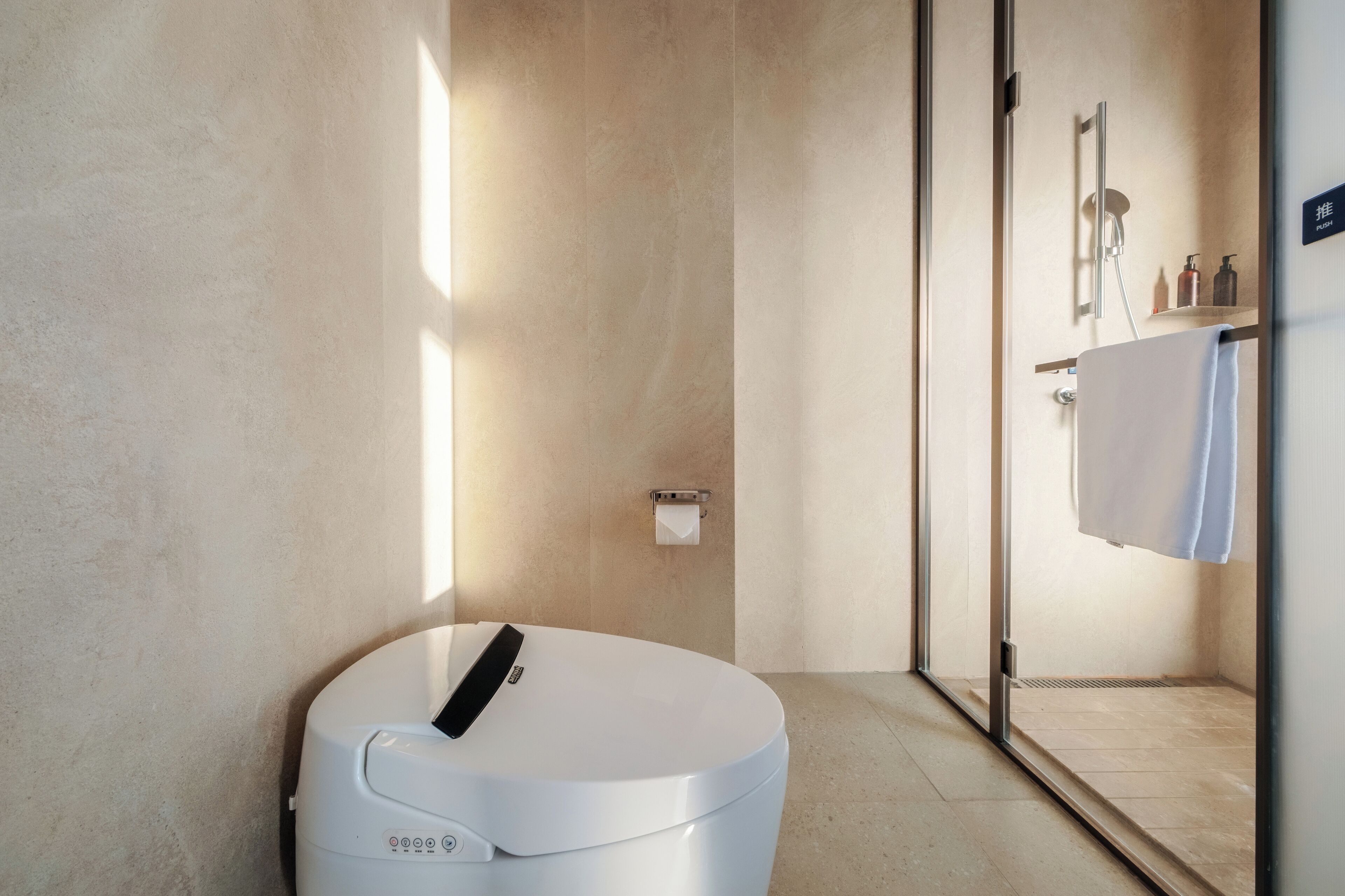 Een moderne badkamer met toilet, douchecabine en handdoekrek.