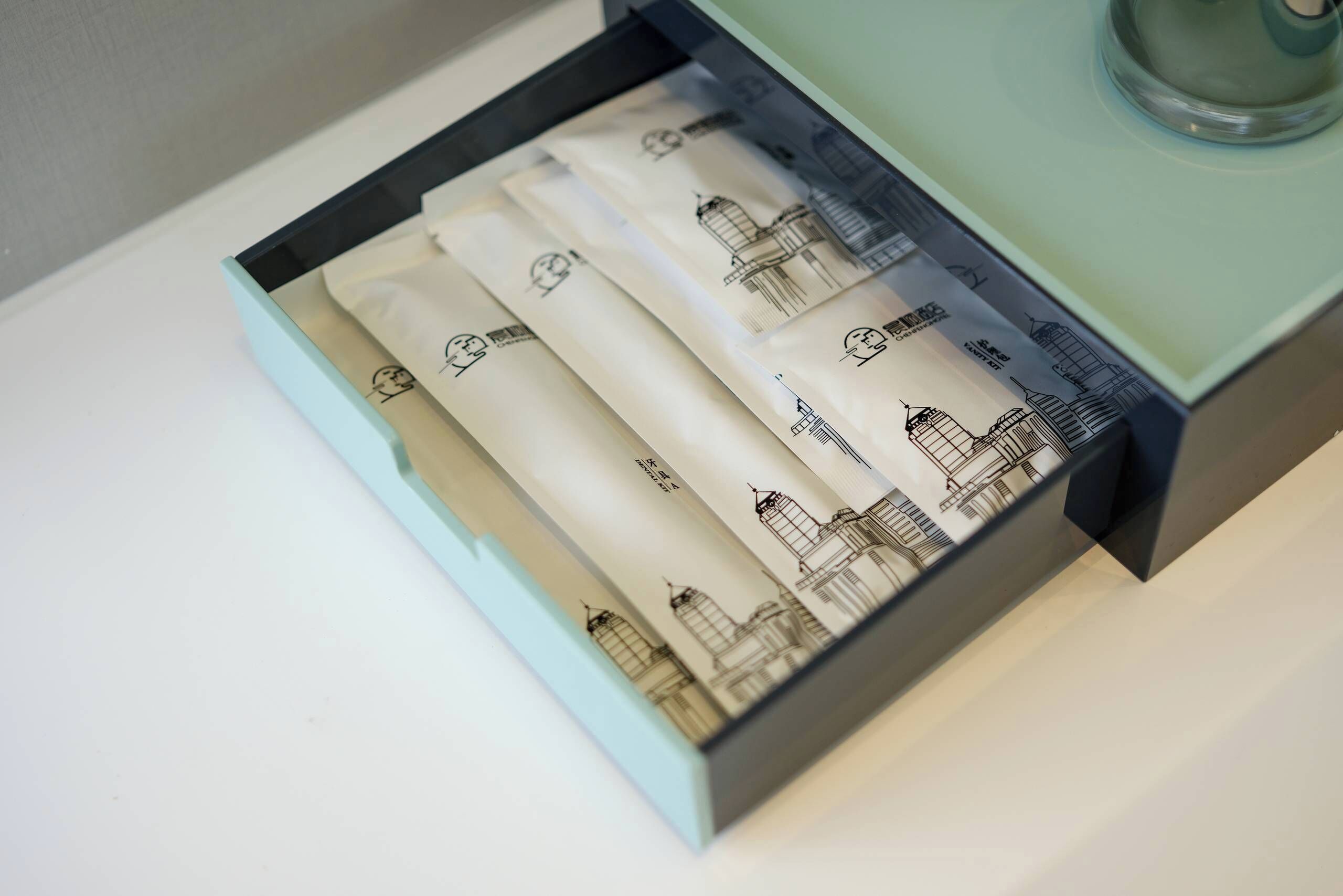 Un cassetto con asciugamani bianchi piegati con cura e disegni architettonici.