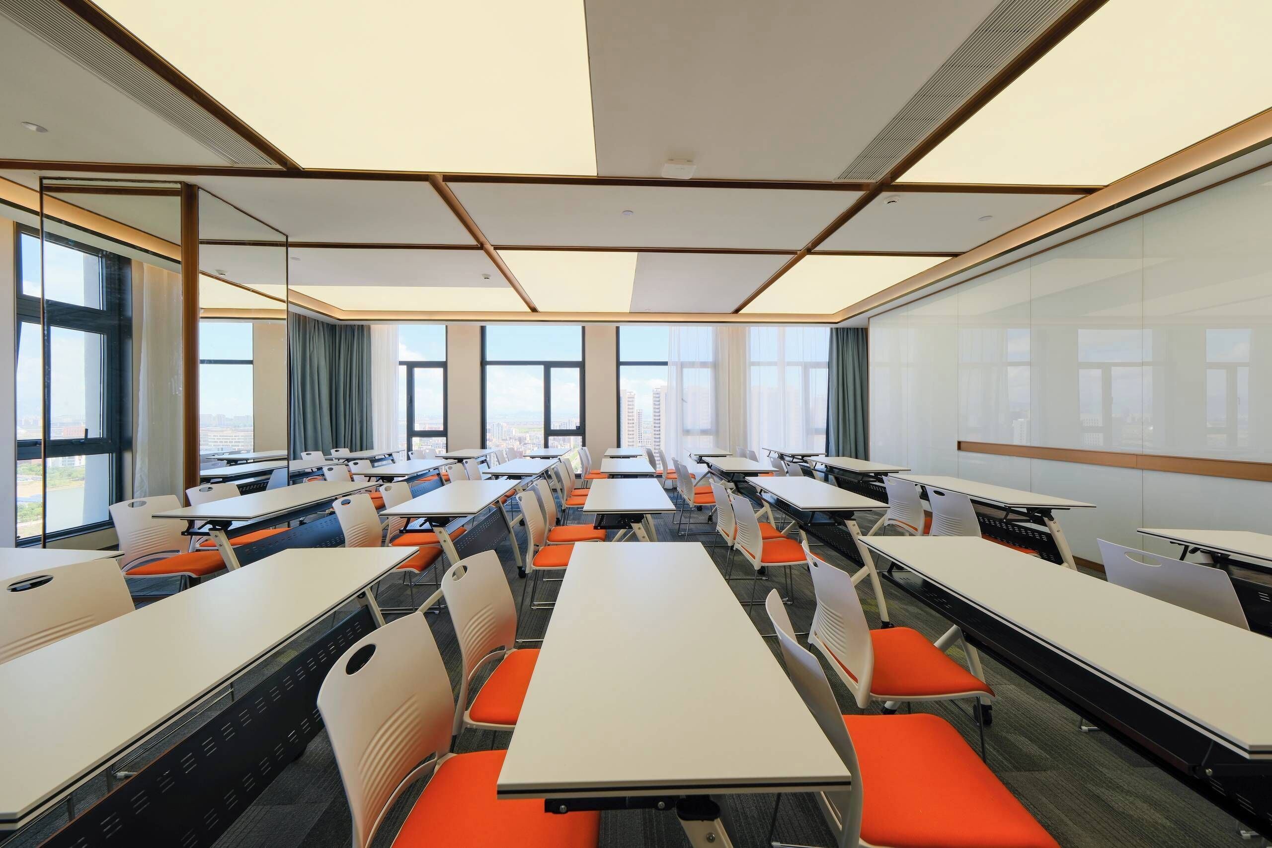 A conference room with multiple tables and chairs, large windows, and a whiteboard.