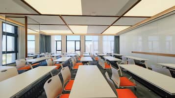 A conference room with multiple tables and chairs, large windows, and a whiteboard.