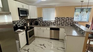 A modern kitchen with white cabinets, a stainless steel refrigerator, a microwave, and a dishwasher. - Enjoyable 1-bedroom apartment with AC in welcoming Nassau (Nassau)