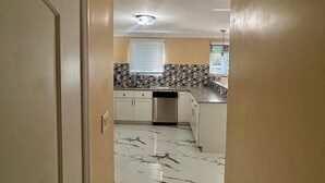 A narrow hallway leading to a kitchen with white cabinets, a stainless steel dishwasher, and a tiled backsplash. - Enjoyable 1-bedroom apartment with AC in welcoming Nassau (Nassau)