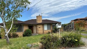 Uma casa térrea com chaminé de tijolos, varanda frontal e caixa de correio.