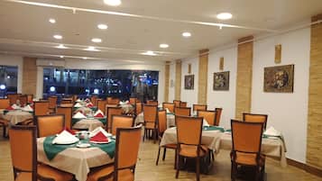 A dining area with multiple tables and chairs, each set with tablecloths and napkins.