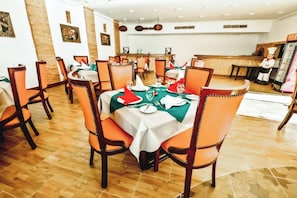 A dining area with wooden flooring, orange upholstered chairs, and tables set with white tablecloths and red napkins. - Palma Di Sharm Resort (Sharm El Sheikh)