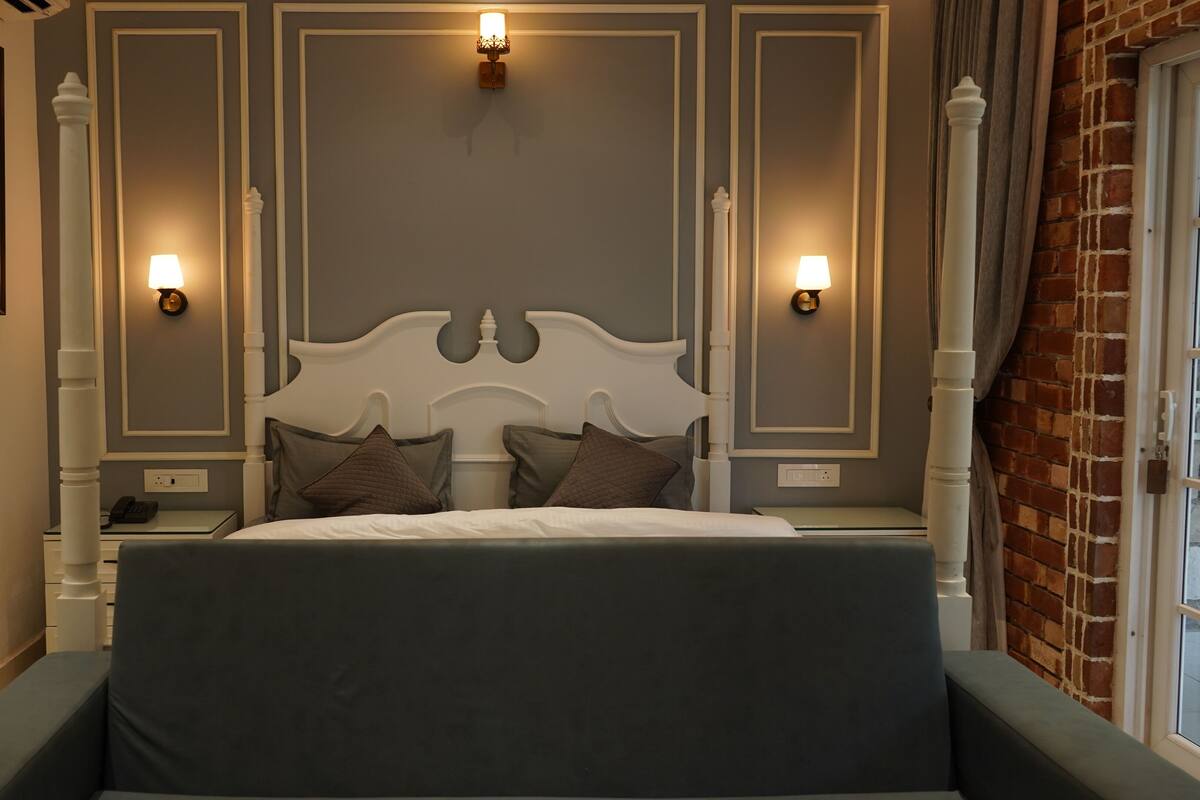A bedroom with a large bed, two bedside tables, a nightstand, and two wall-mounted lamps.