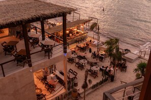 Eine Strandbar mit Außenbestuhlung und einem Reetdach.