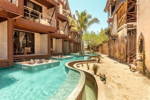 Un resort con varias piscinas, un camino de arena y edificios de madera.