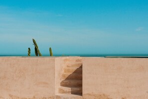 Une structure en béton avec un escalier menant à un niveau supérieur, d’où l’on a une vue sur une étendue d’eau.