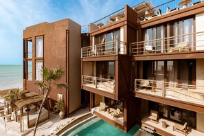 Un hotel de varios pisos con balcones, piscina y vista a la playa.