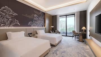 A hotel room with two beds, a large artwork on the wall, a desk with a lamp, and a TV.