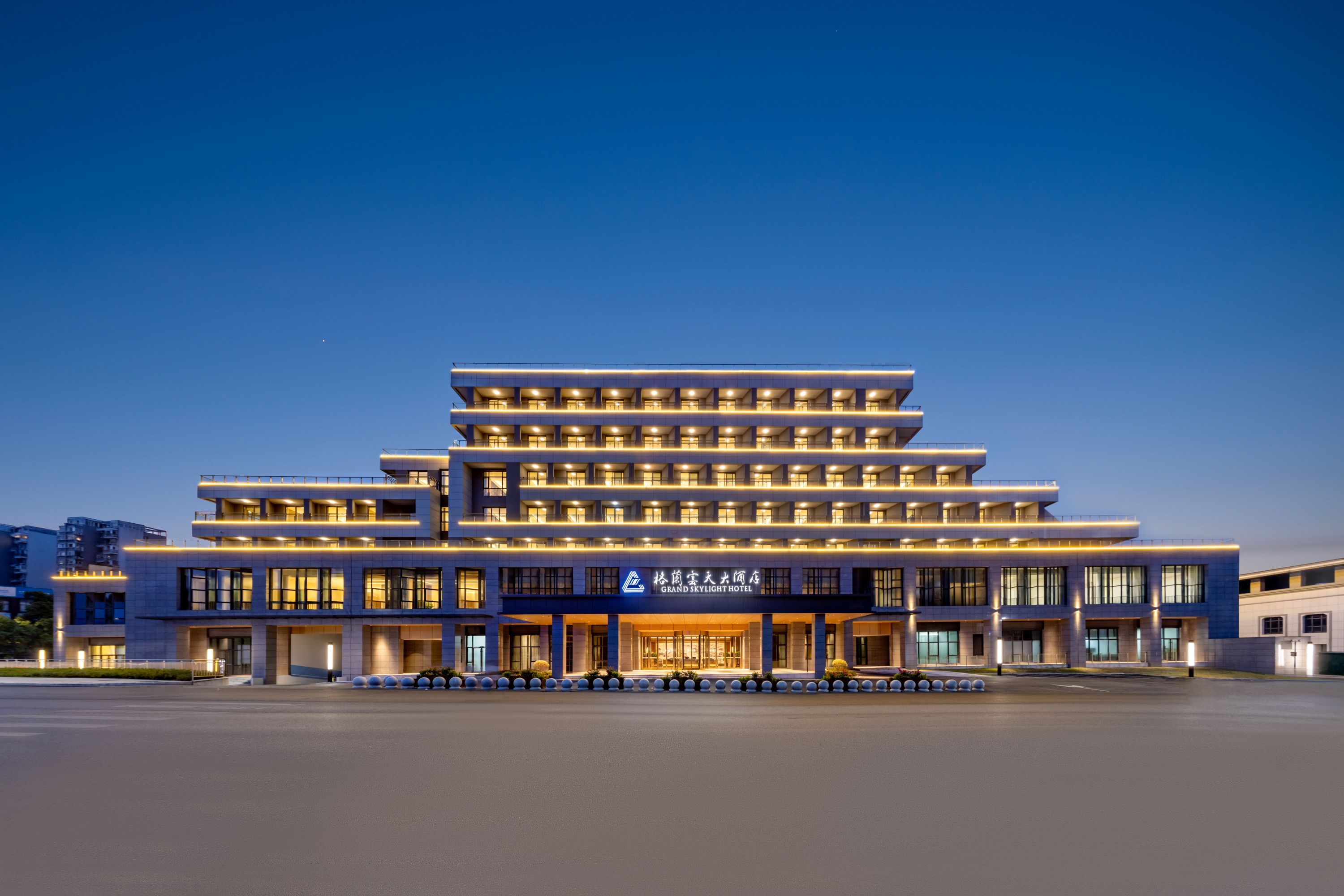 A multi-story hotel with a modern design, featuring a prominent entrance and a series of balconies.