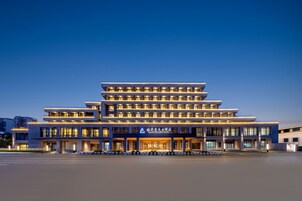 Un hotel de varios pisos con un diseño moderno, que cuenta con una entrada destacada y una serie de balcones.
