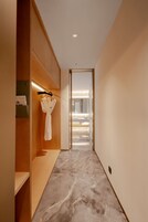 A modern hallway with a wooden wardrobe, a robe hanging on a rack, and a marble floor.