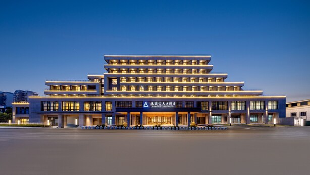 Ein mehrgeschossiges Hotel mit modernem Design, das durch einen markanten Eingang und eine Reihe von Balkonen gekennzeichnet ist.