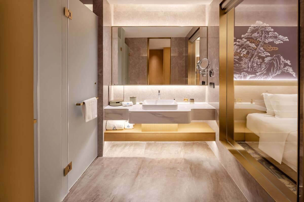 Un baño moderno con un espejo grande, un lavabo y un inodoro.