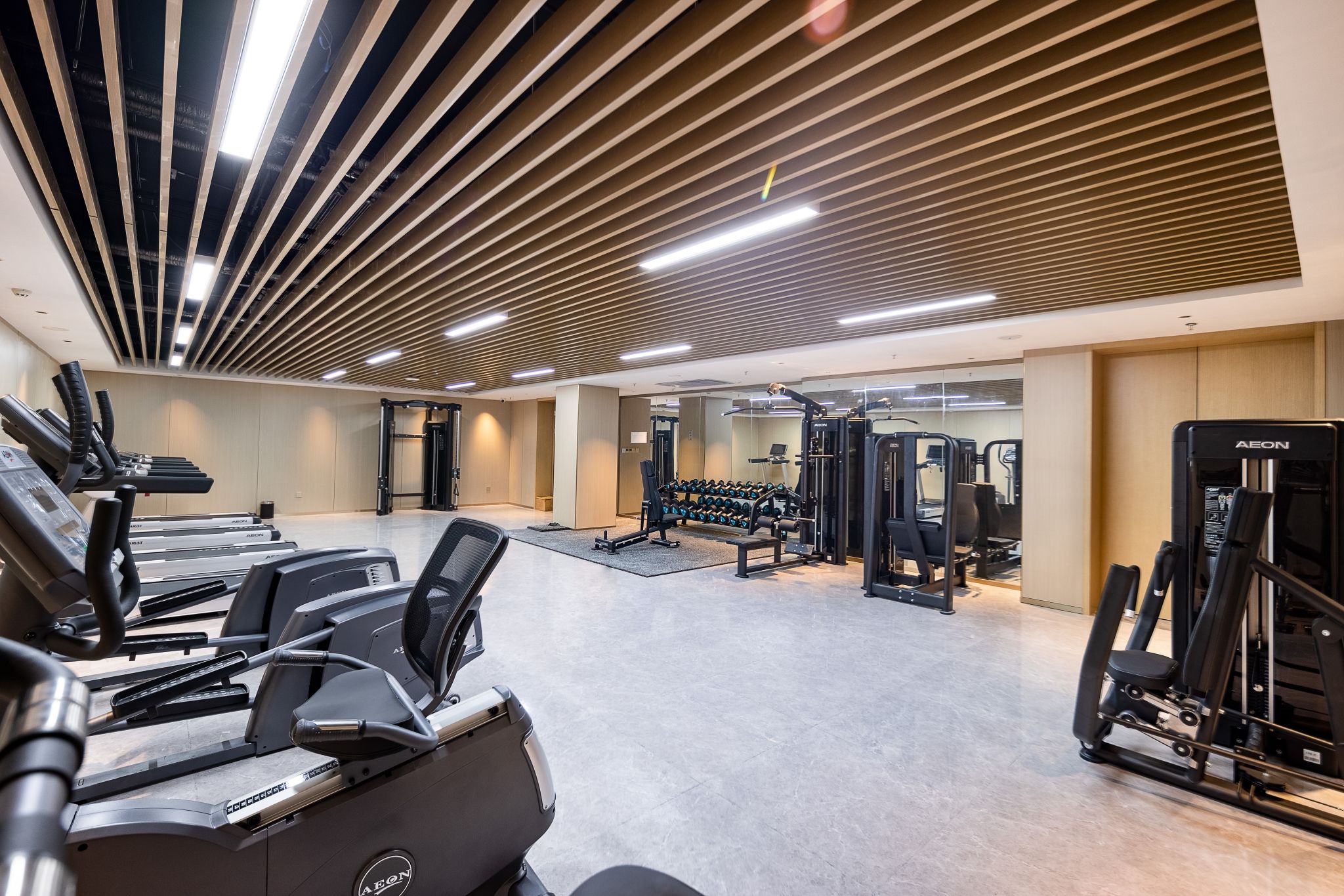 Une salle de sport moderne équipée de tapis de course, d’appareils de musculation et de poids libres.