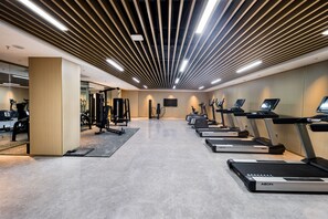 Een moderne sportschool met loopbanden, gewichtstoestellen en een grote spiegel.