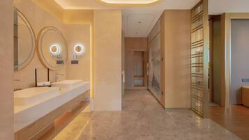 A modern bathroom with two sinks, illuminated mirrors, and a hallway leading to a room with a large window.
