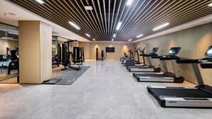 Ein modernes Fitnessstudio mit Laufbändern, Kraftgeräten und einem großen Spiegel.